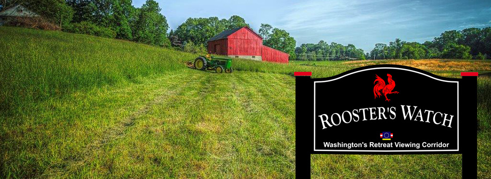 A large field with a barn and house in the distance. Rooster's Watch Sign.