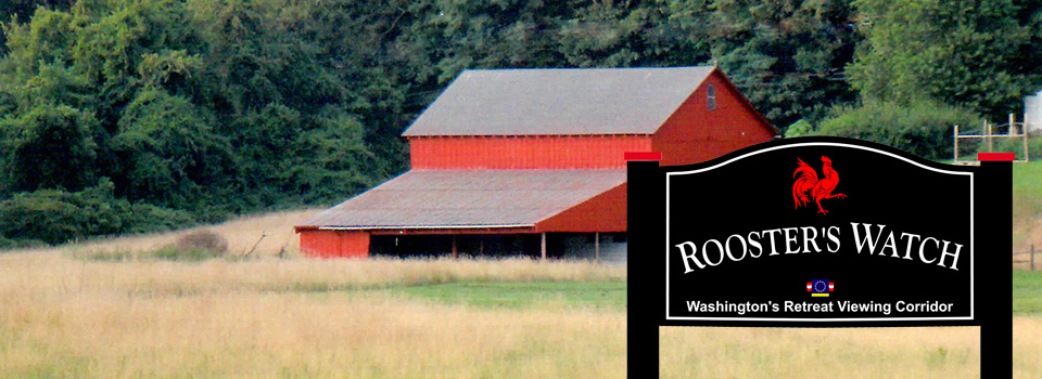 A large field with a barn and house in the distance. Rooster's Watch Sign.